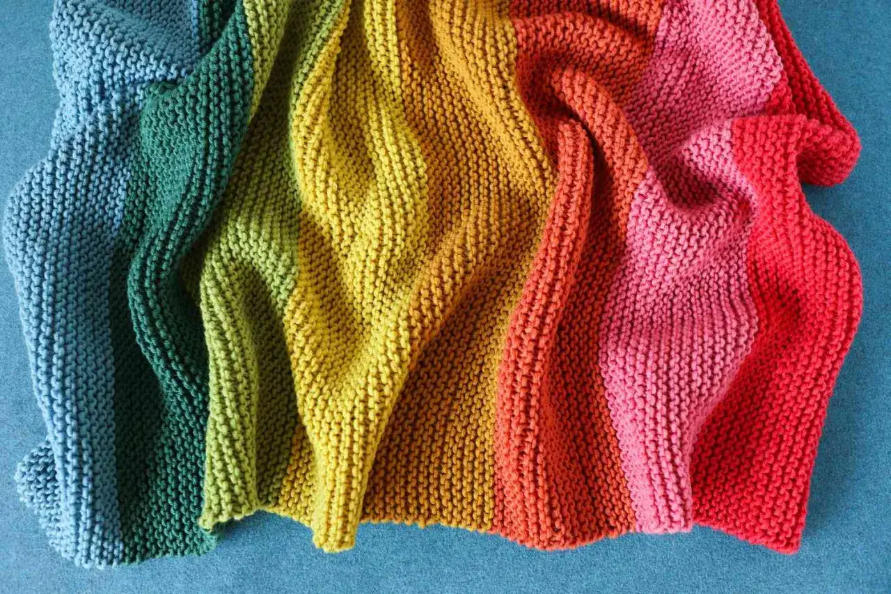 Coperta arcobaleno lavorata a maglia, con spiegazioni dettagliate per creare questo capolavoro di lavori ai ferri.
