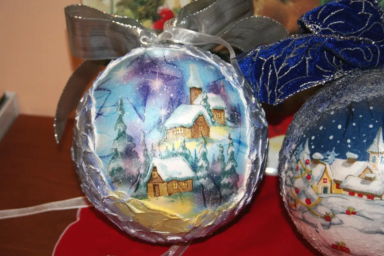 Palline natale decoupage con paesaggi innevati e fiabeschi, decorate con nastri argentati e blu.