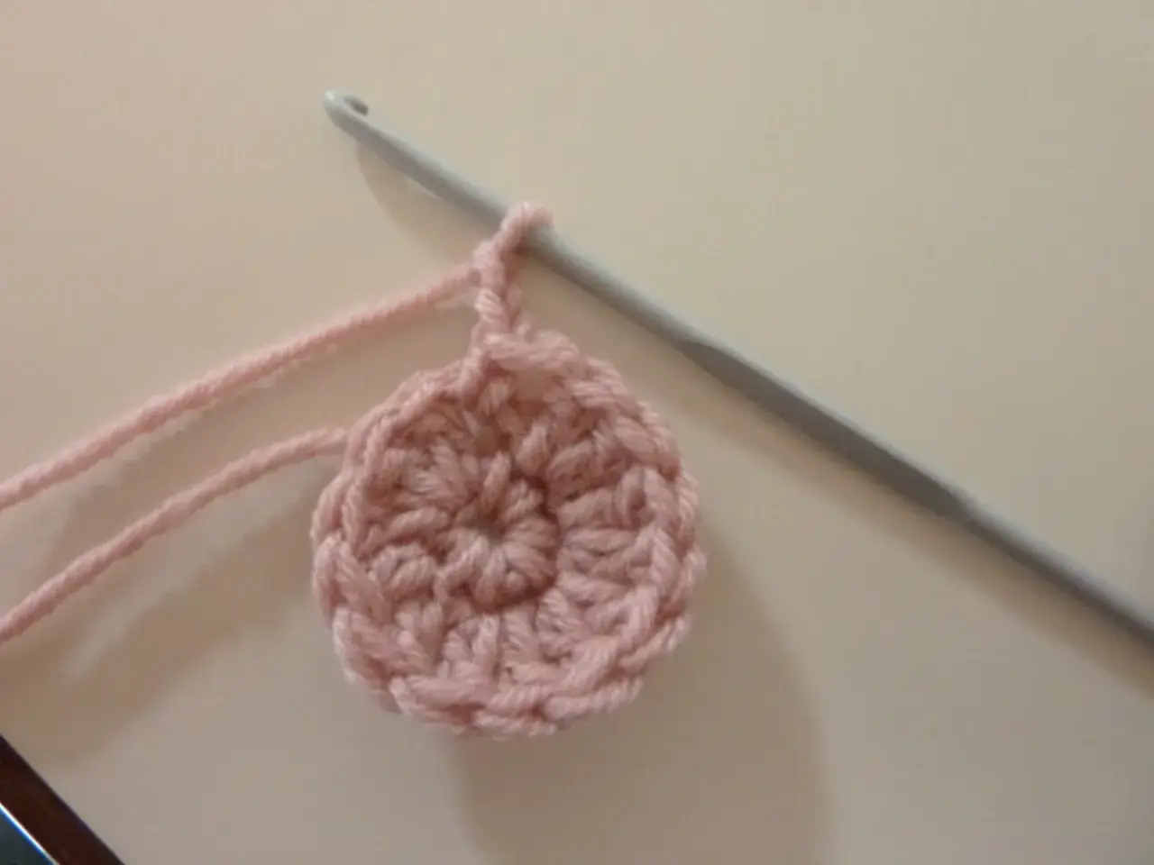 Cerchio rosa all'uncinetto con uncinetto doppia punta grigio.