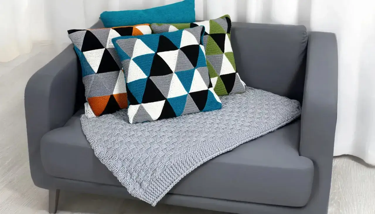 Cuscini geometrici e coperta grigia, perfetti per i tuoi lavori a maglia per la casa.