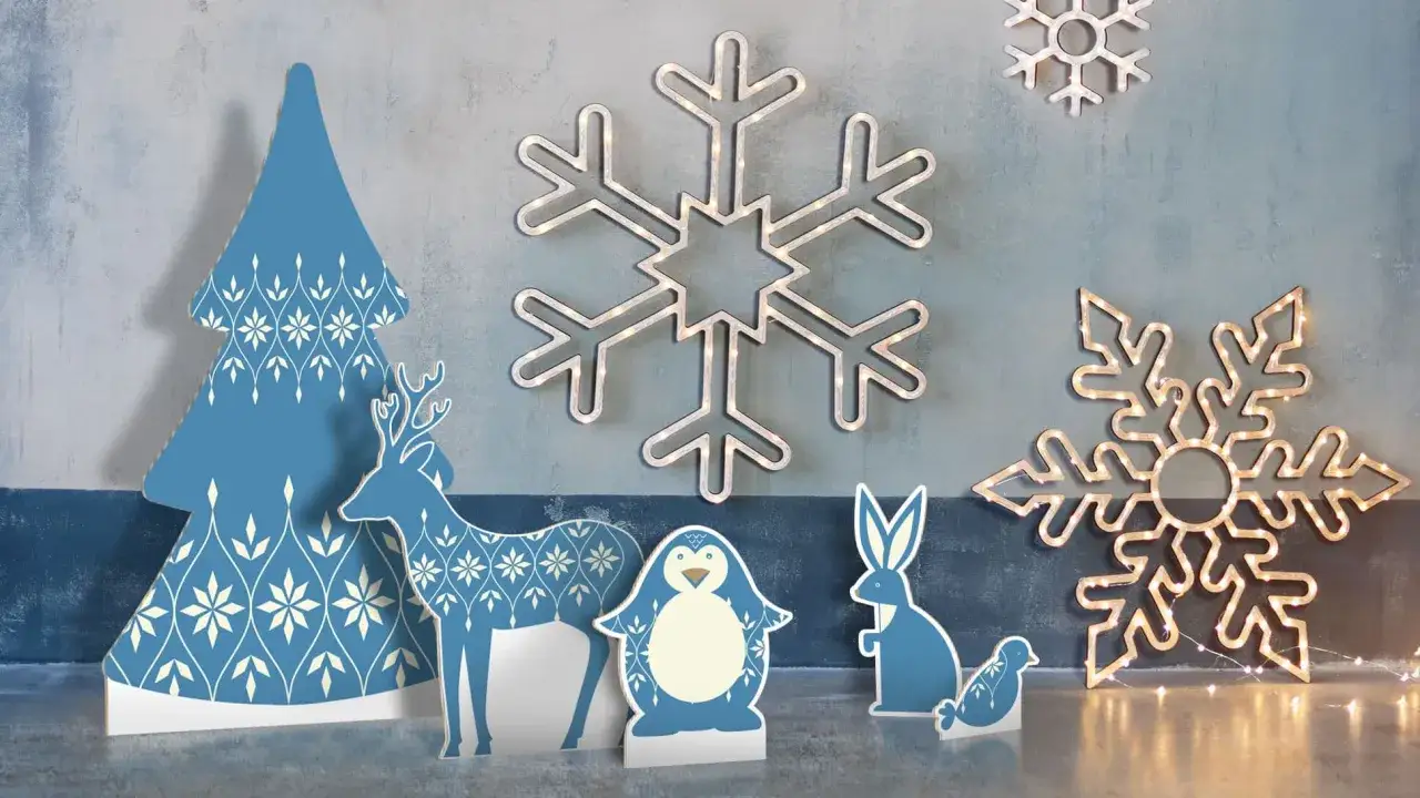 Sagome natalizie grandi: un albero, un cervo, un pinguino, un coniglio e un uccellino, con fiocchi di neve luminosi sullo sfondo.