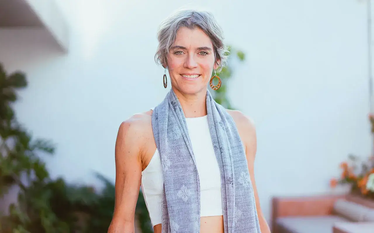 Donna sorridente con sciarpa grigia, un esempio di quanto deve essere lunga una sciarpa da donna per un look casual ed elegante.