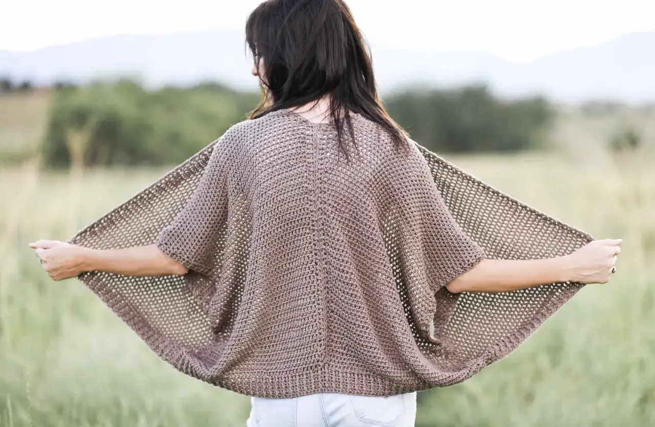 Donna con un cardigan all'uncinetto marrone, perfetto per chi cerca schemi gratis per creare capi unici.