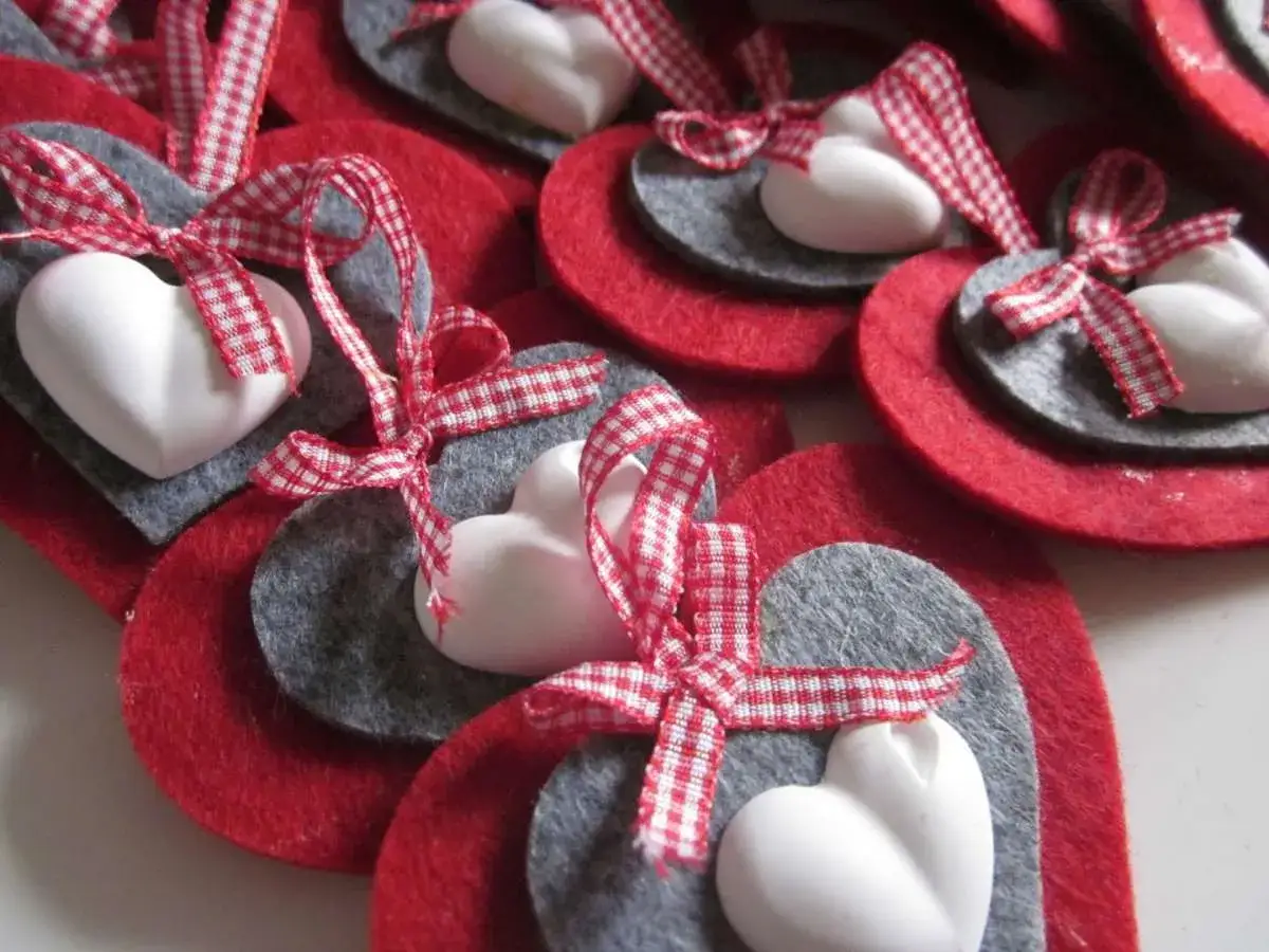 Cuori rossi e grigi di fogli di feltro, decorati con fiocchi a quadretti e piccoli cuoricini bianchi.