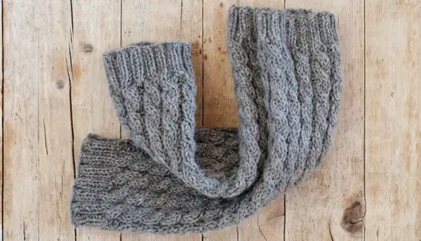 Un caldo scaldacollo grigio lavorato a maglia con trecce. Perfetto per scoprire cosa fare con 100 grammi di lana.
