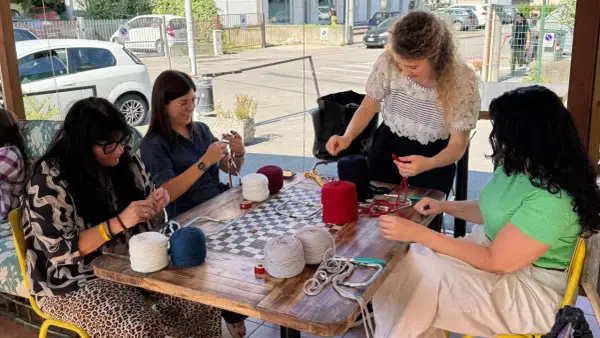 Donne lavorano a maglia con gomitoli di lana colorata al **café lana**.