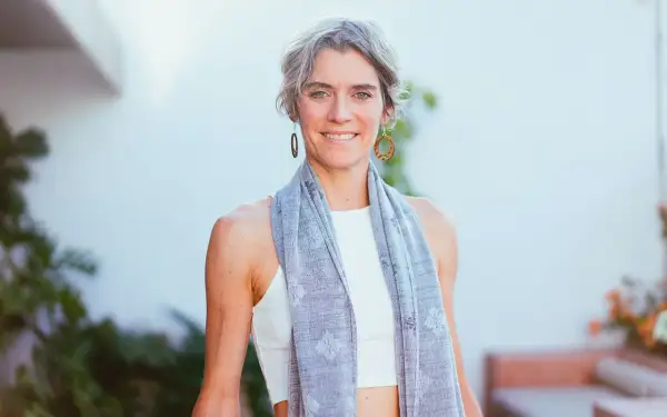 Donna sorridente con sciarpa grigia, un esempio di quanto deve essere lunga una sciarpa da donna per un look casual e chic.