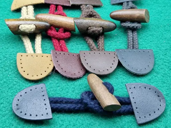 Bottoni alamari fai da te in legno e pelle, pronti per essere cuciti su capi d'abbigliamento.