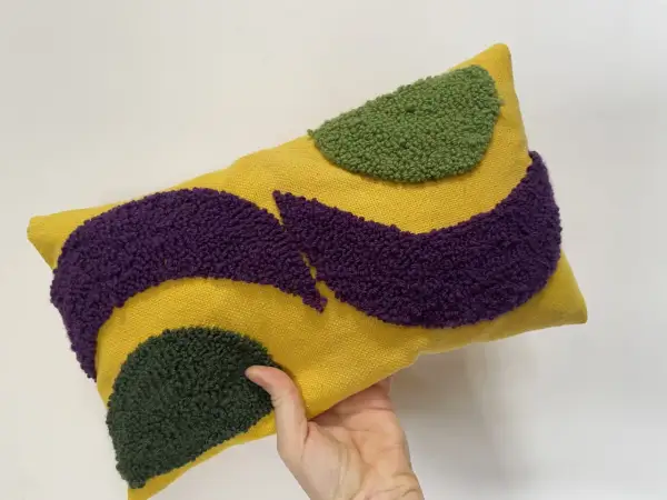 Cuscino rettangolare giallo con motivi astratti in microspugna viola e verde.