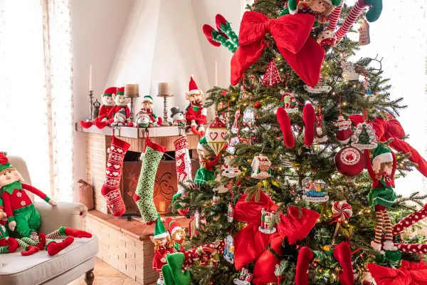 Albero di Natale addobbato con elfi, calze e fiocchi rossi. Un esempio di come decorare l'albero di natale fai da te con tanti dettagli.