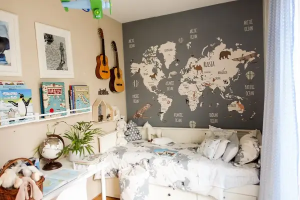 Camera da letto con mappa del mondo e decorazioni tema viaggio: aerei, mongolfiere, animali e chitarre.